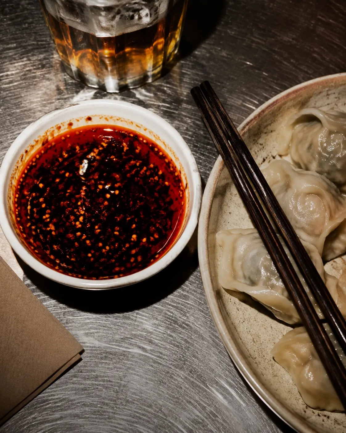 Dumplings, sauce and a beer on a warmly lit table